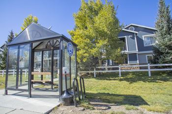a bus stop with a glass shelter in front of a house